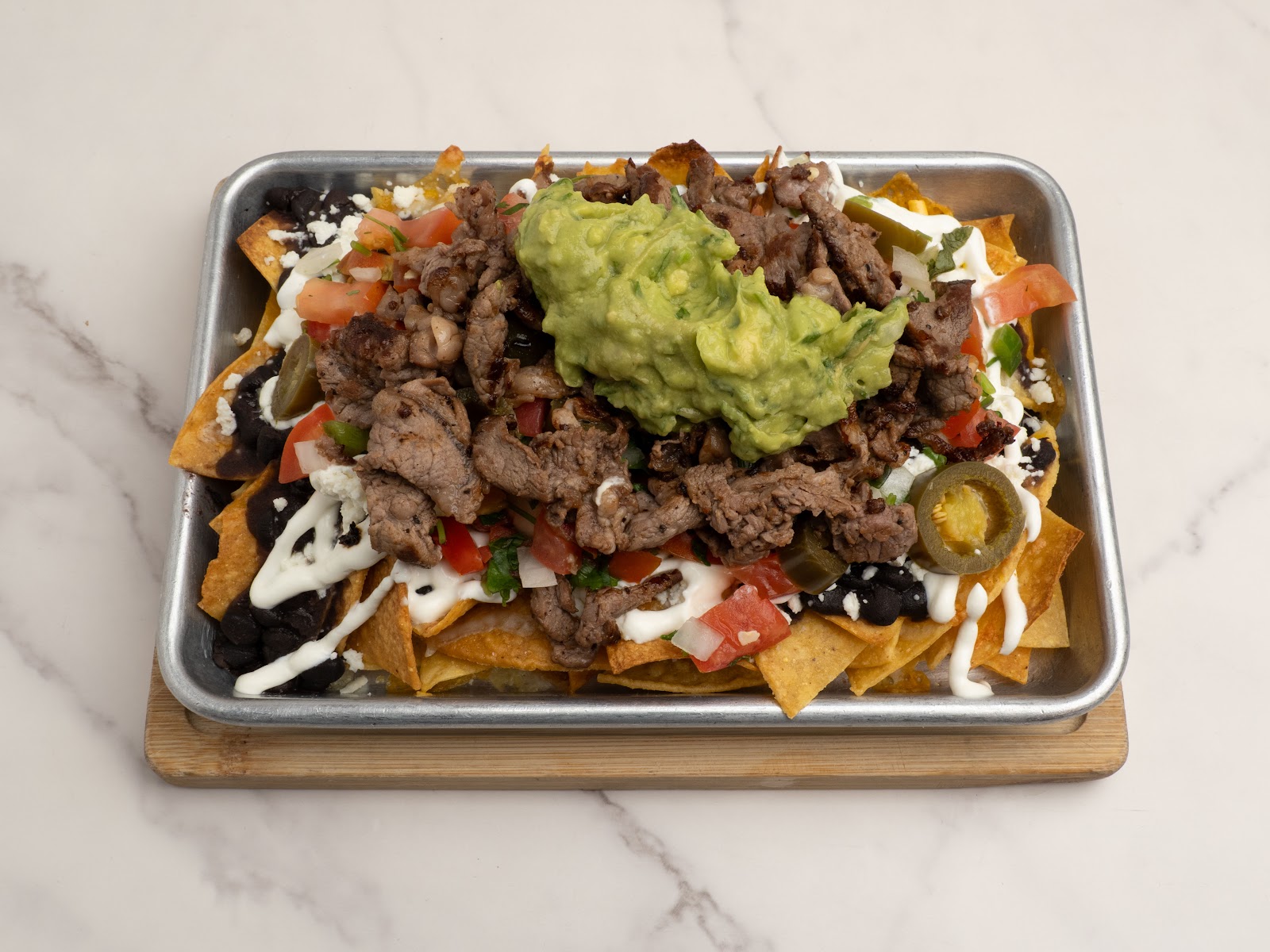 Nachos con queso — crispy chips smothered in melted cheese and toppings